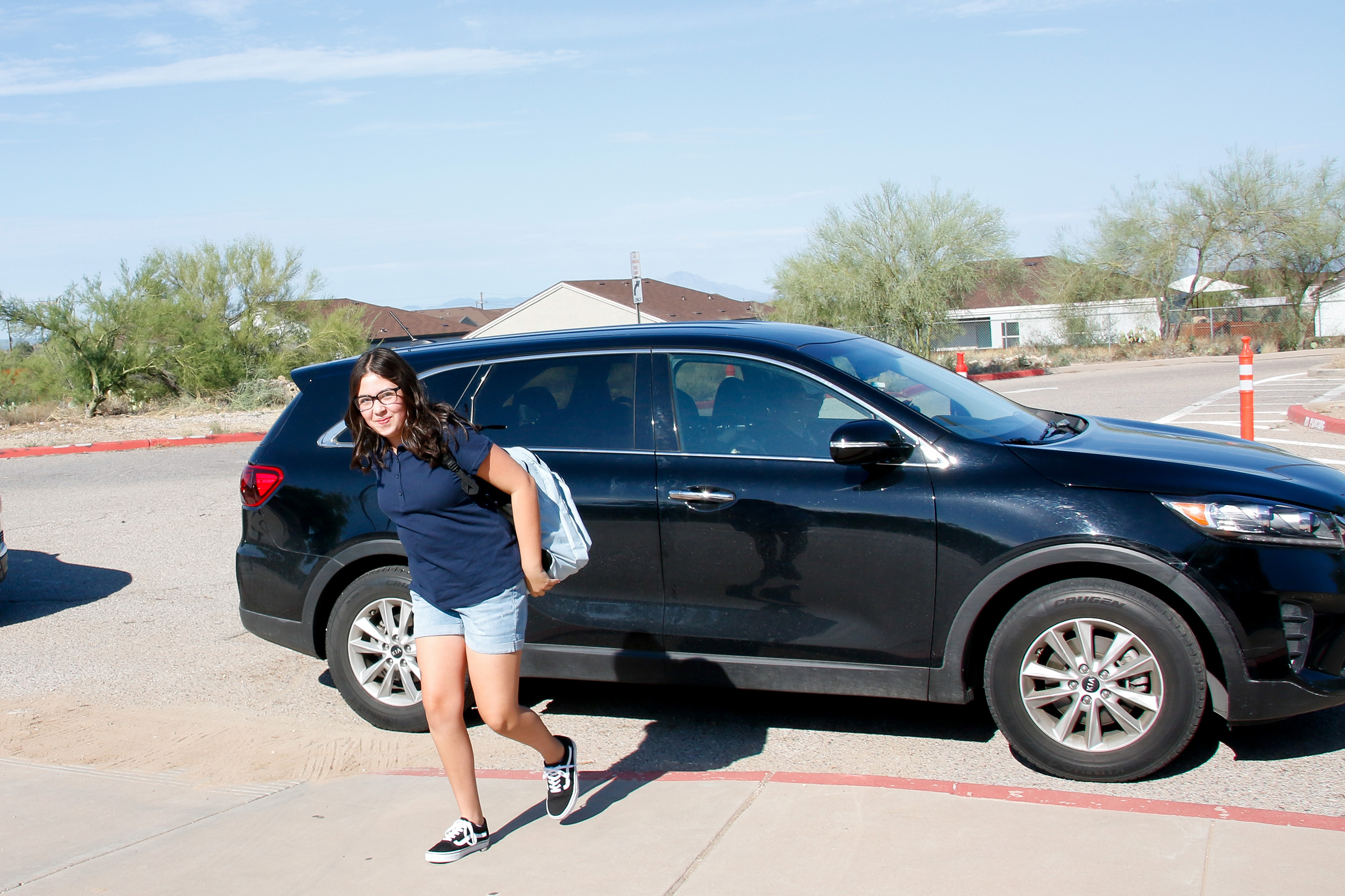 A middle school girl walks away from her family's car on the first day of school